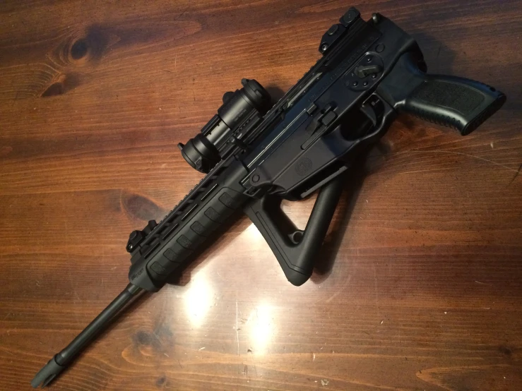 a black rifle with black handles and scopes laying on a wood table