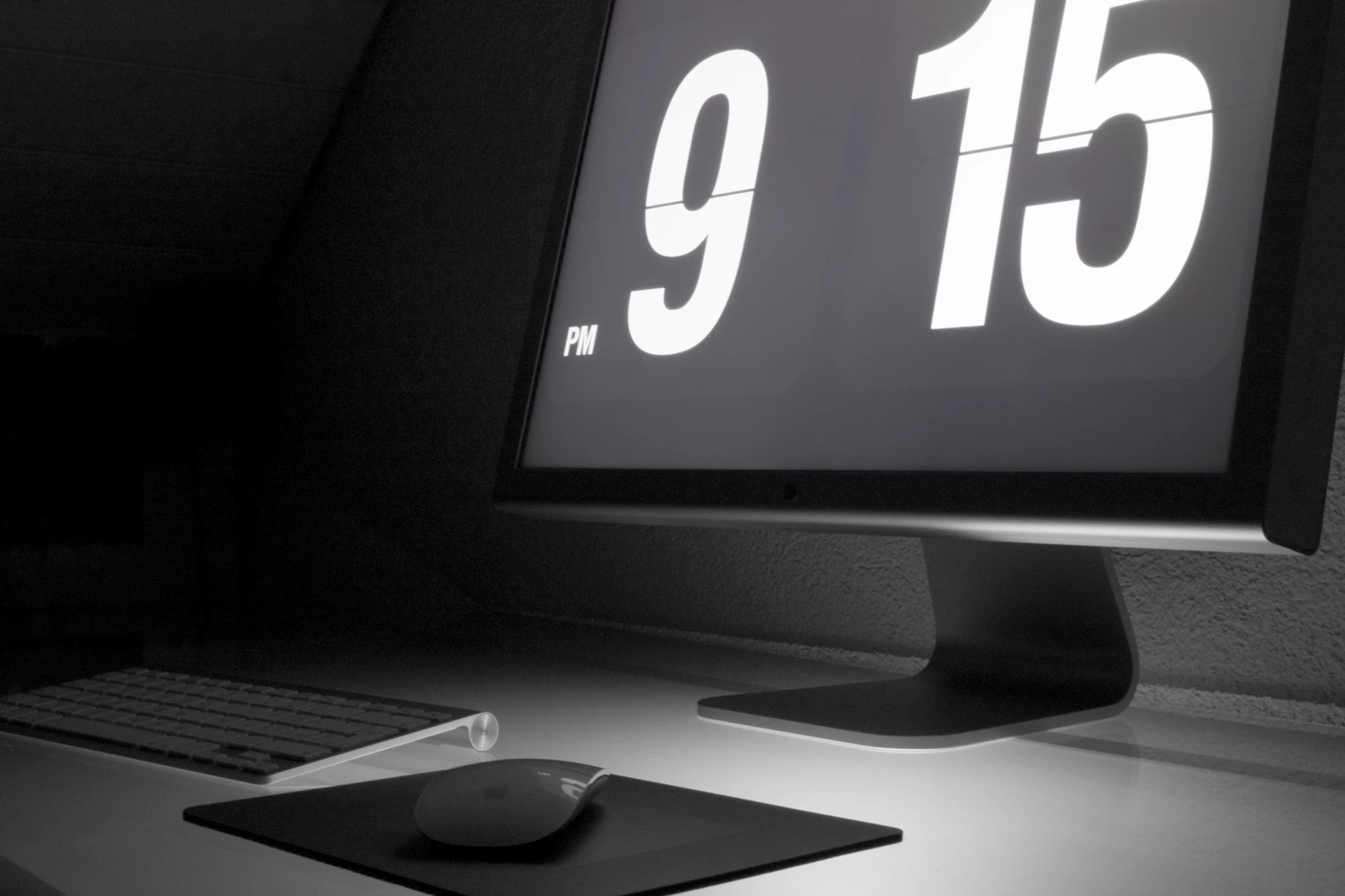 an illuminated monitor and mouse sits on a desk