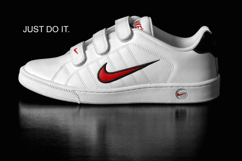 the nike tennis shoe has a white upper with a red nike logo
