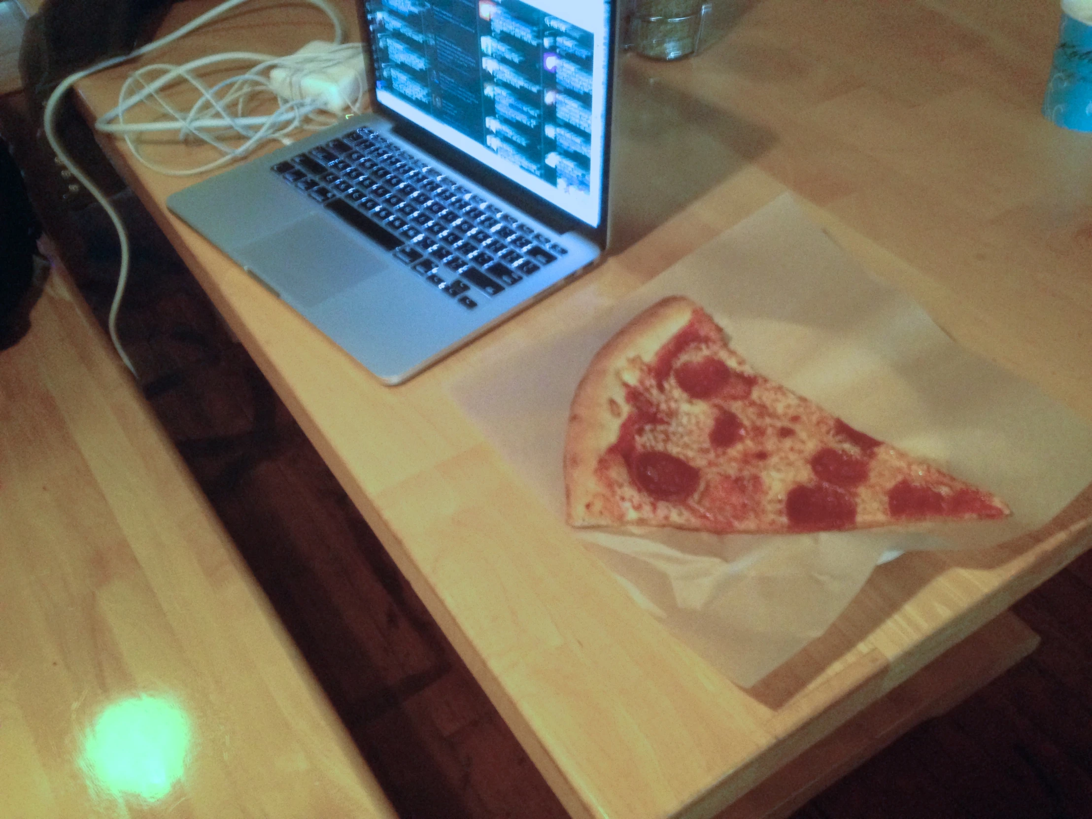 a piece of pizza that is next to a laptop