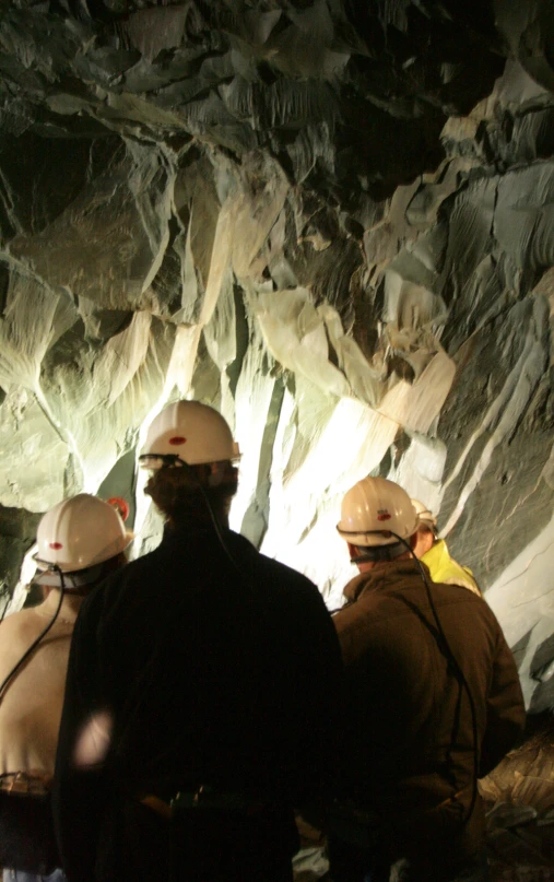 people wearing helmets sitting together in a cave