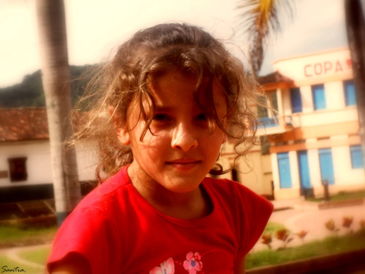 a little girl posing for a picture with a building behind her