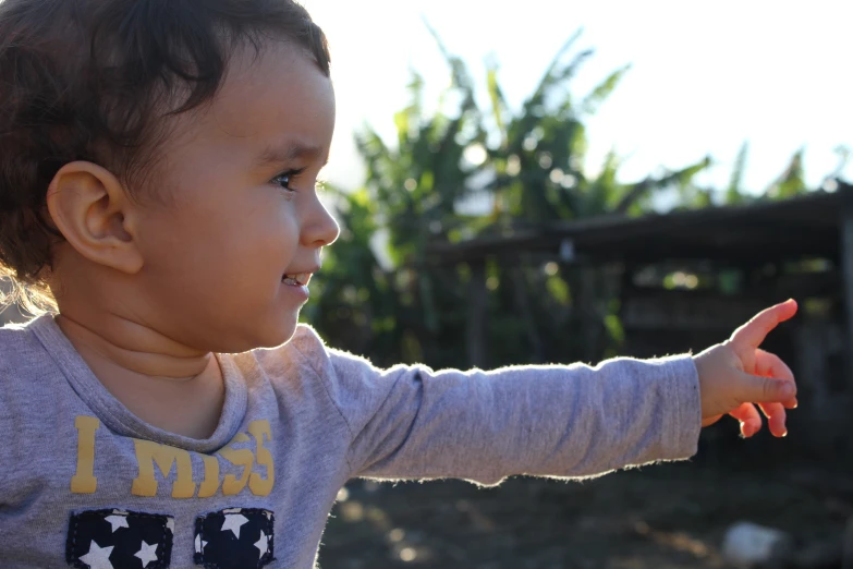 a toddler pointing towards soing with trees in the background