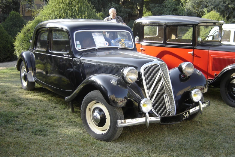 two old black antique cars sitting on the grass