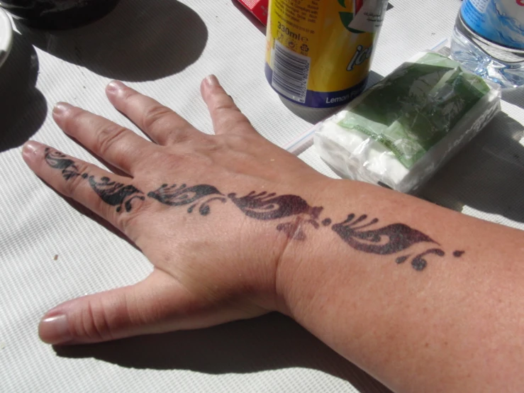 a hand with tattoos on the palm and some bottles