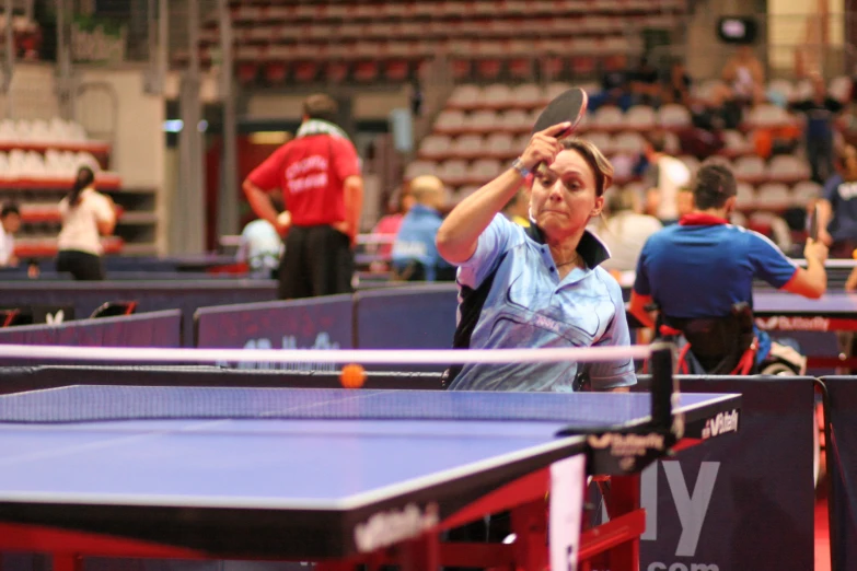 there are two women playing table tennis in an arena