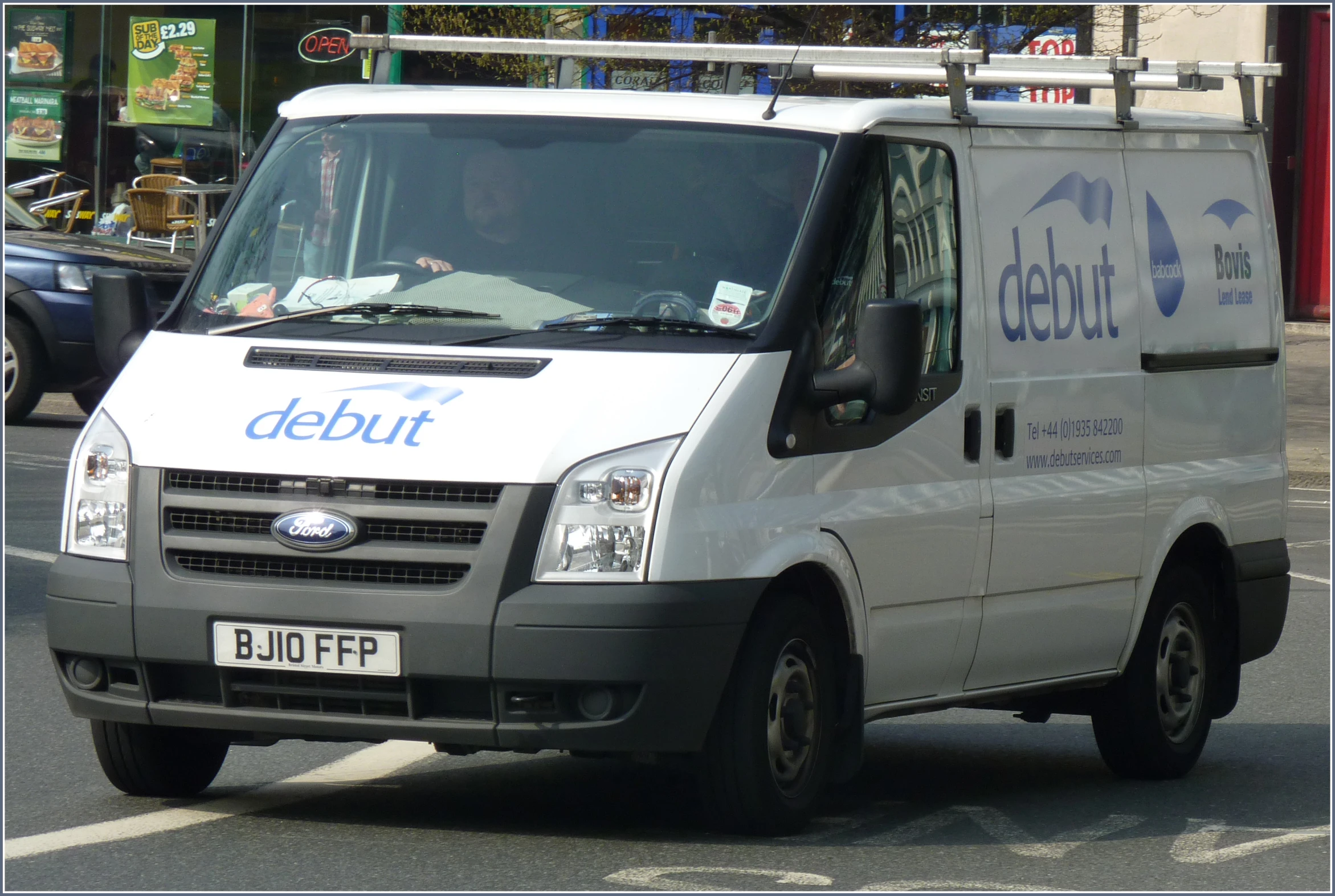 a car driving down the road with an icebuut van behind it