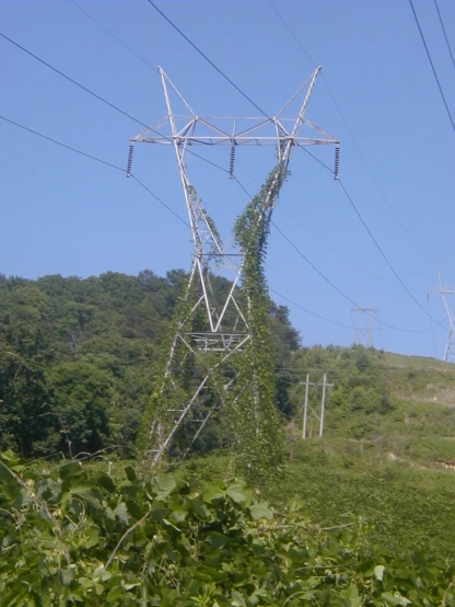 a very large power line by a grassy hill