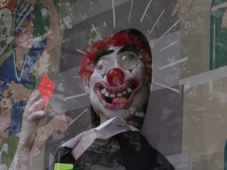 a clown with an odd expression holds a plastic candy bar