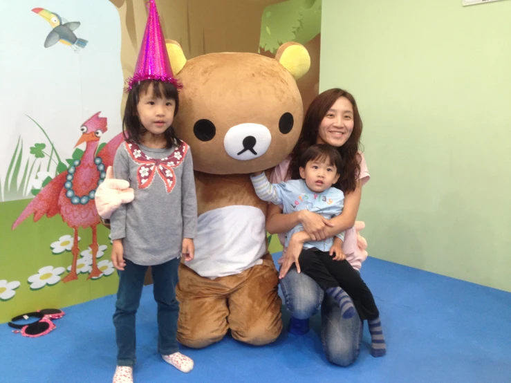 children sitting on a large brown stuffed animal