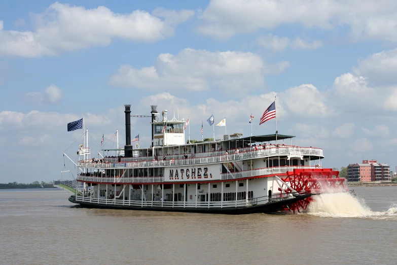 a large boat moves through the water by some american flags