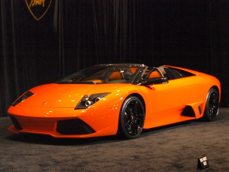 a large orange sports car is on display