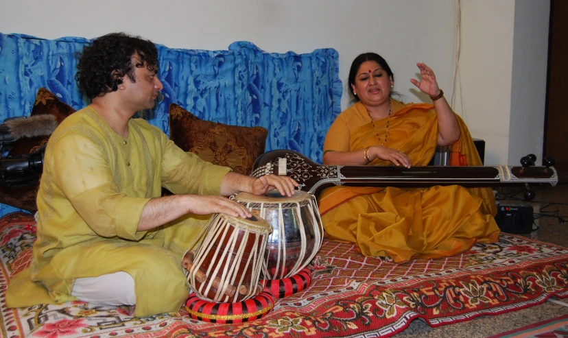 a man and woman sitting next to each other playing drums