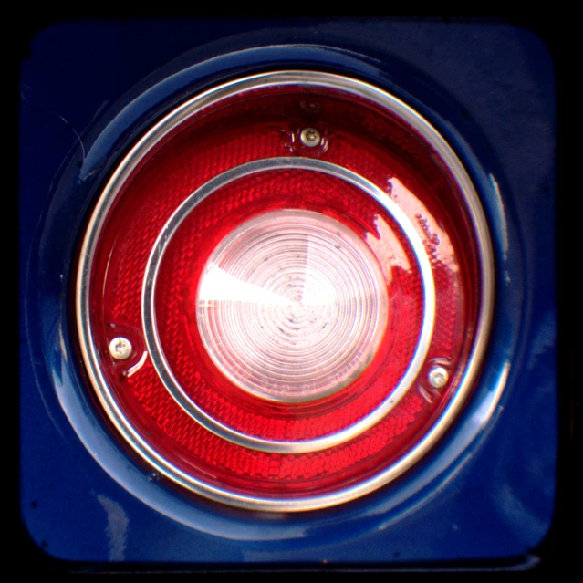 the rear end of a blue car with red headlights