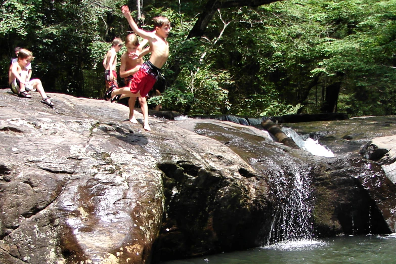 three people climbing over a waterfall while others watch