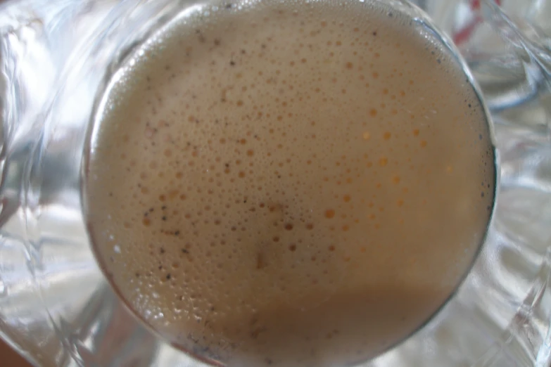 an empty drink cup with foam sitting on a clear plate