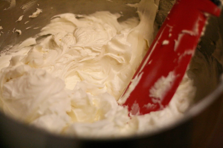 a red spatula in a bowl full of batter