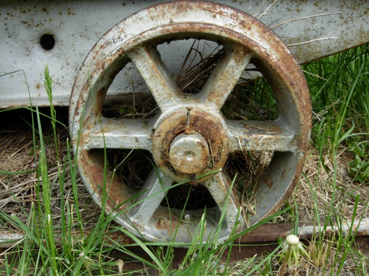 an old rusted wheel is in the grass