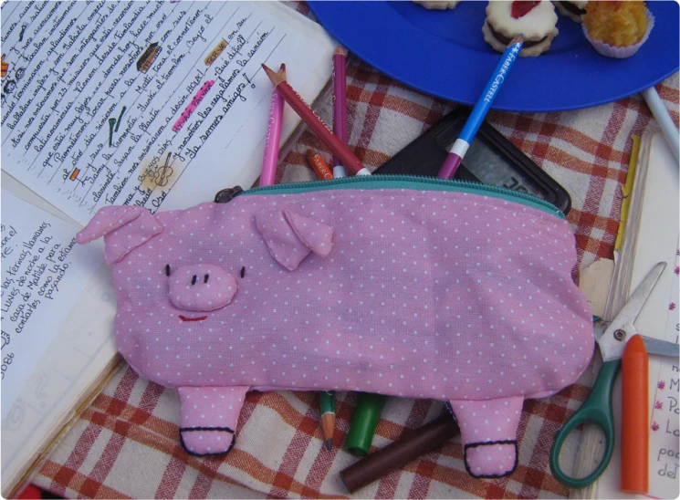 a cute pig pencil case sitting on top of some scissors and scissors