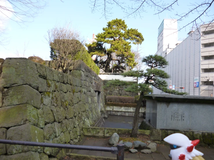 a fenced area with rocks and an old rock wall and trees