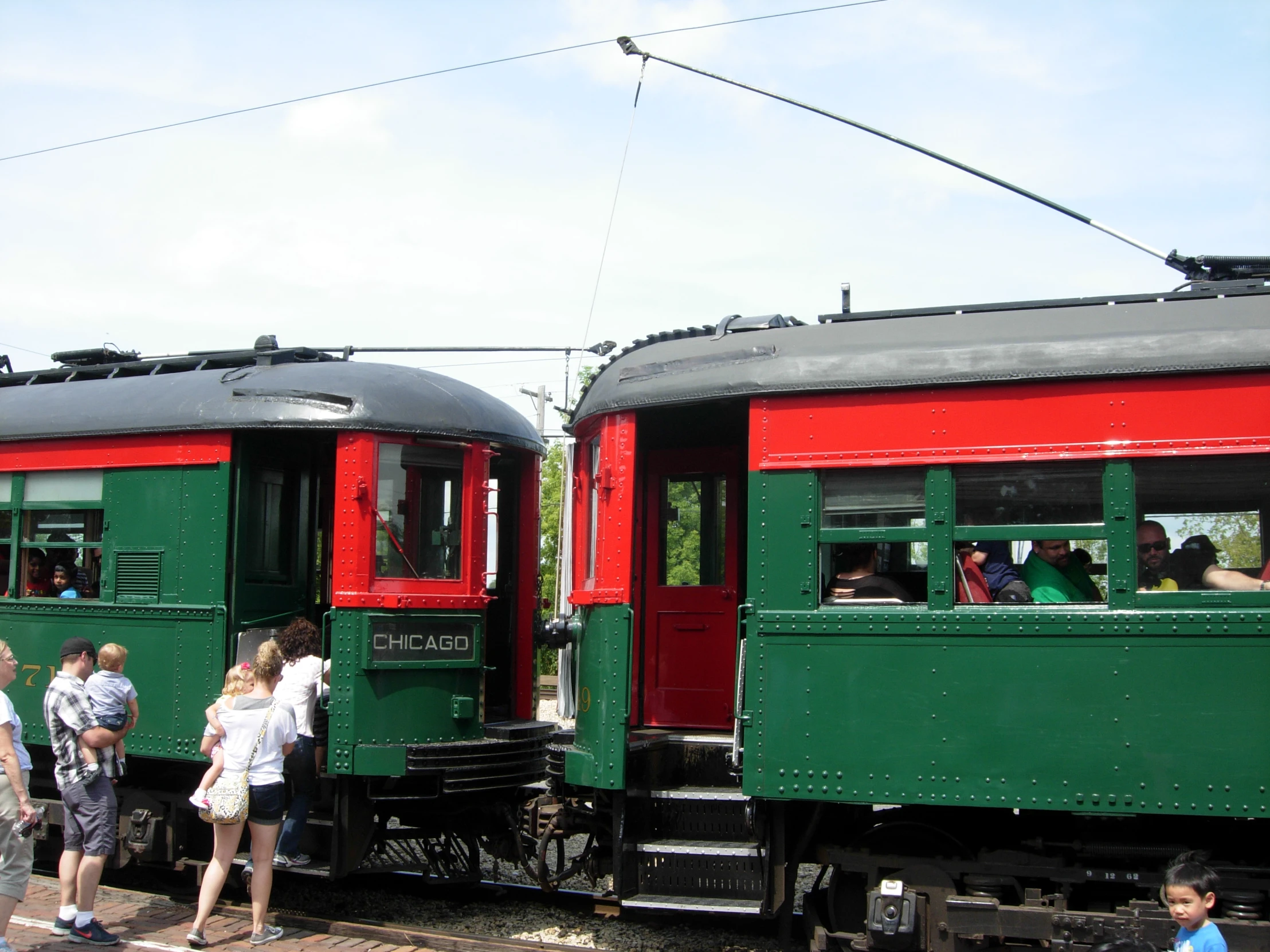 people standing in front of green and red passenger trains