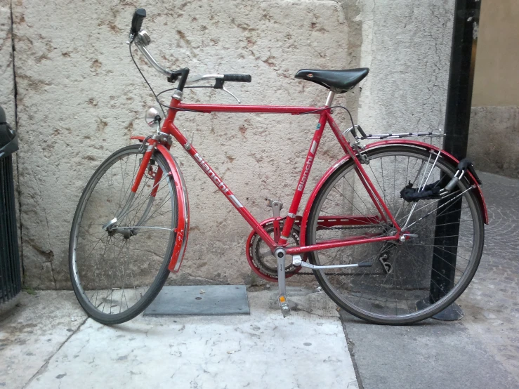 a red bicycle parked against the side of a building