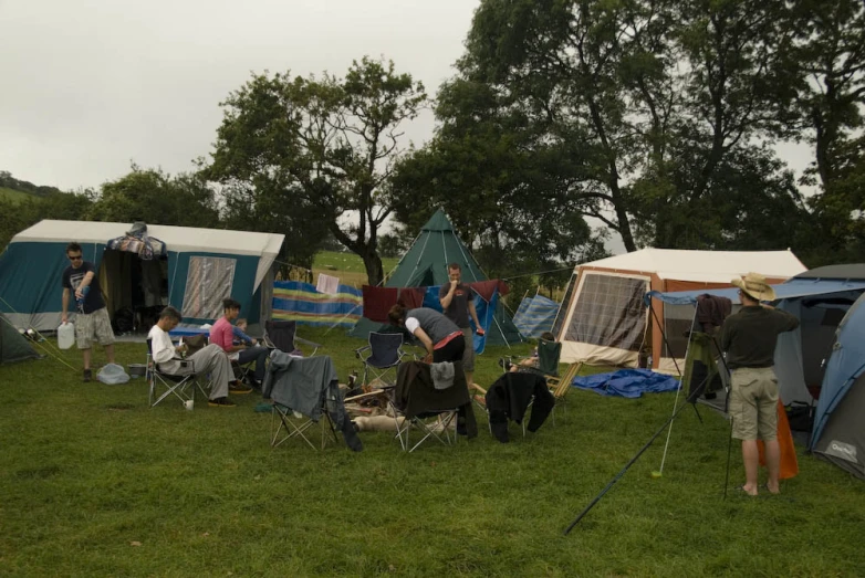 people camping in tents on a grass covered hill