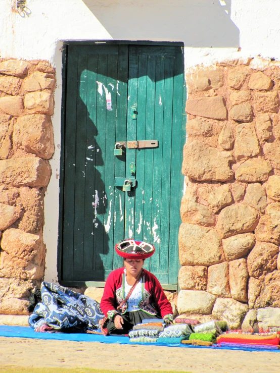 the person is sitting on a blanket in front of a door