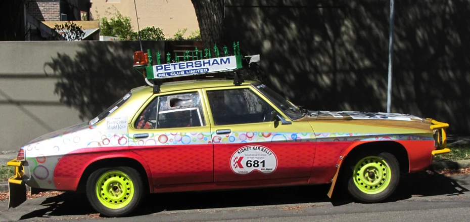 the colorful vintage car is parked on the side of the street