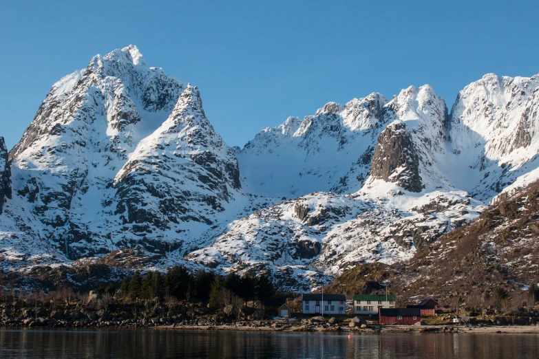 large snow - covered mountains rise high above the ocean