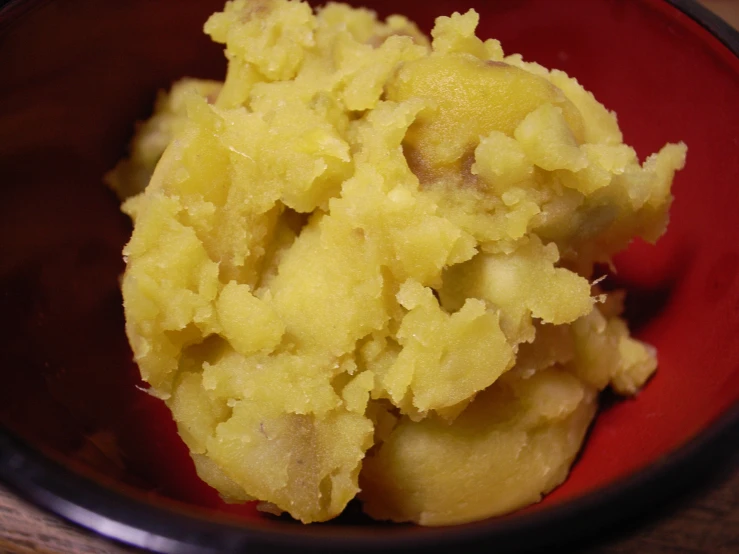 a bowl filled with mashed potatoes on top of a wooden table