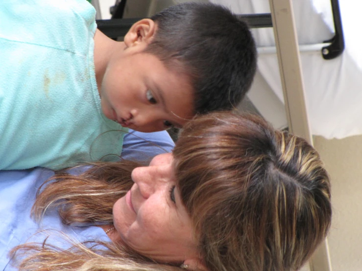 a woman smiles as a boy lays in a bed