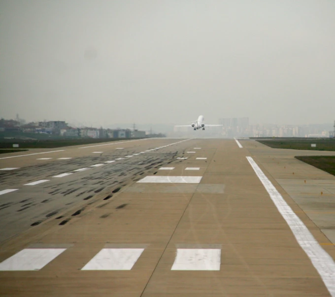 the view of a runway at an airport as a jet comes in for landing