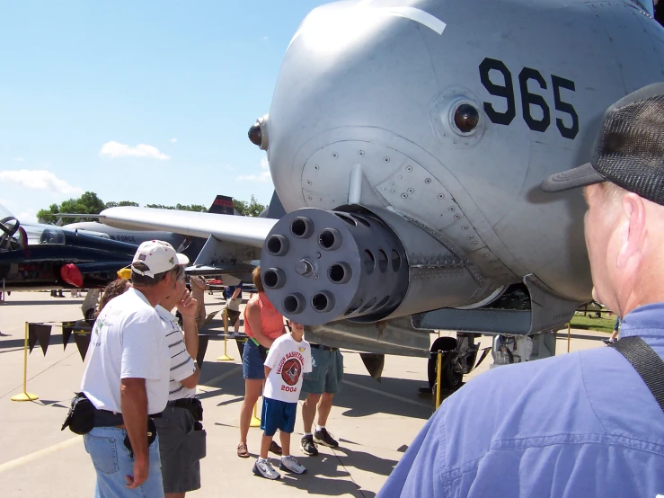 several people look at an old military plane