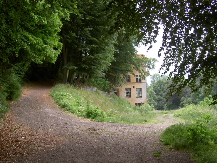 a dirt road in front of an abandoned house
