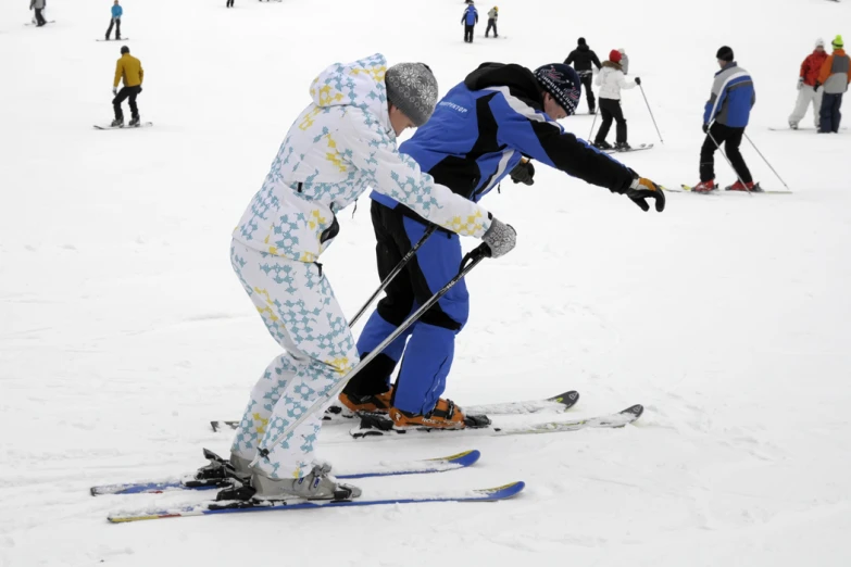 a couple of men riding skis across a snow covered slope