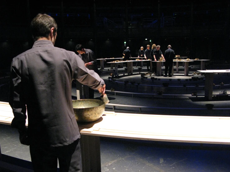 a man holds a large bowl in a dark auditorium