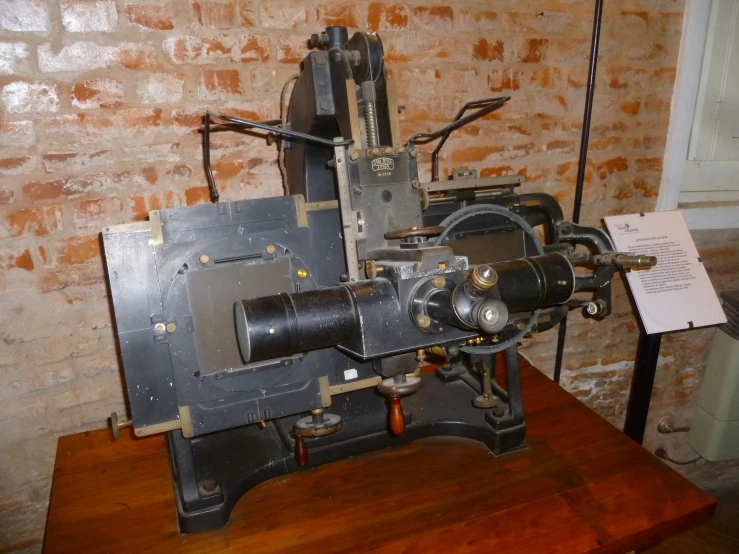 a machine is on a wood table next to a brick wall