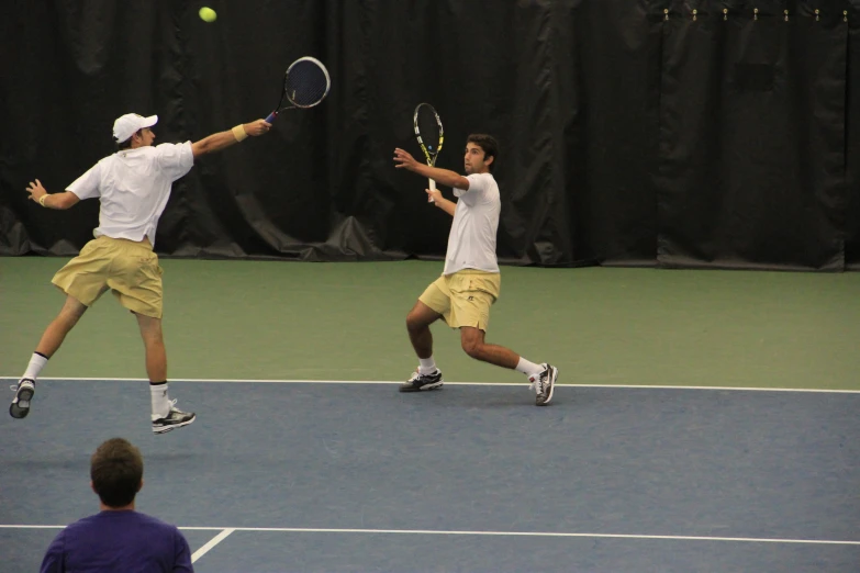 two male tennis players are playing tennis with a crowd watching