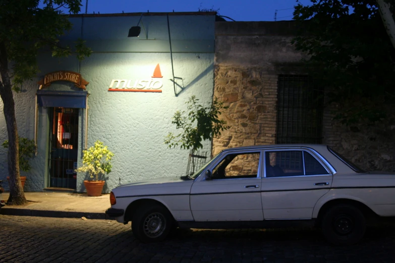 an old car parked outside a building in front of trees