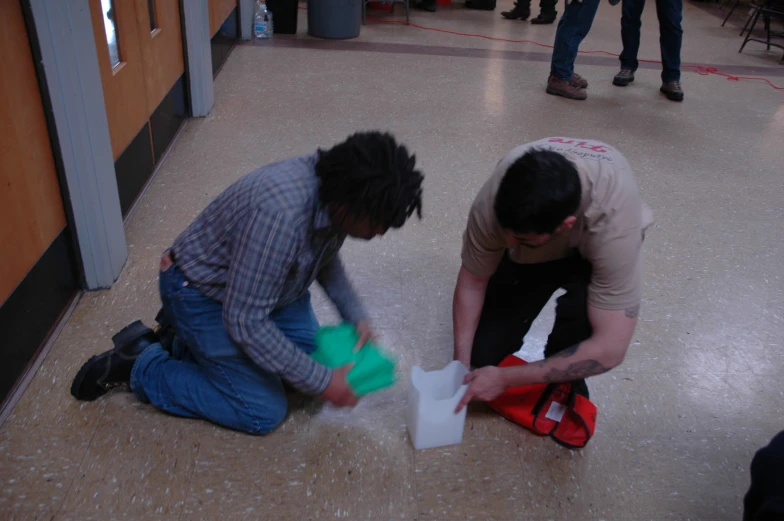 two people sitting on the ground playing with some material