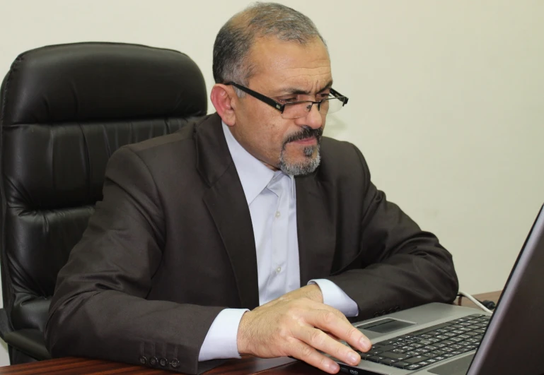 a man is using a laptop on his desk