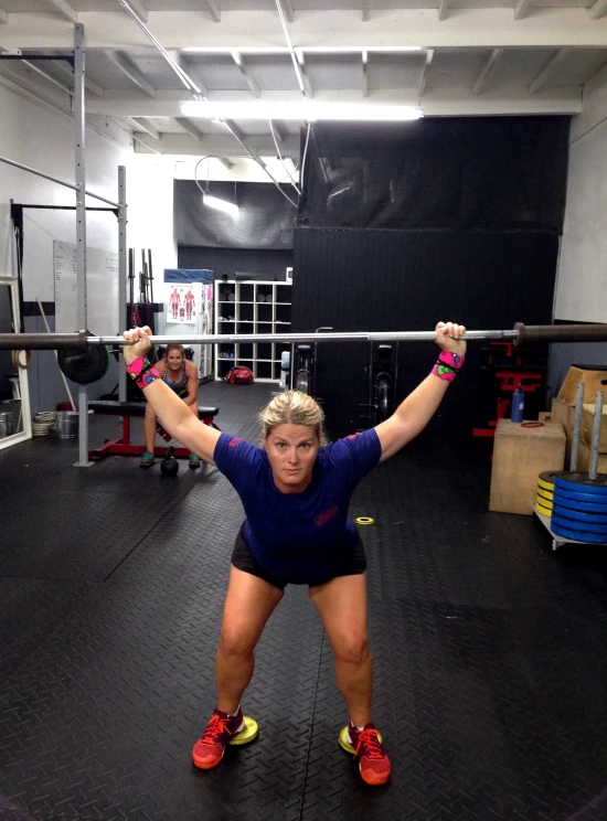 a woman is holding a barbell in an empty gym