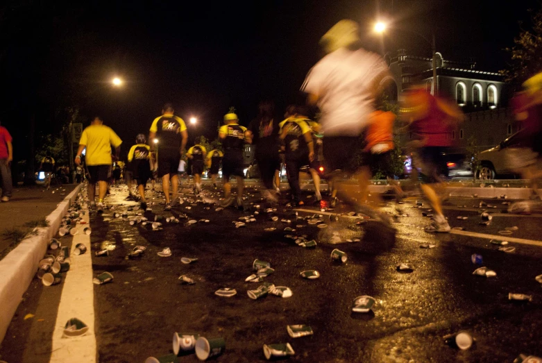 people in yellow vests and neon lights walking near a crowd of trash