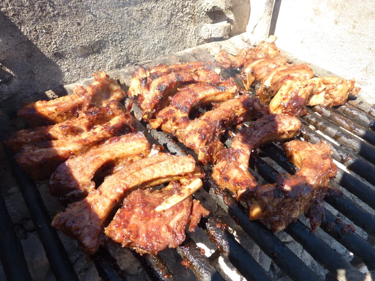 barbecue ribs and steaks are cooking on a grill