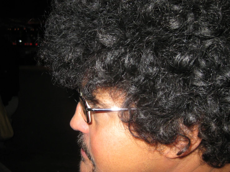 closeup of man with curly hair and glasses on at night