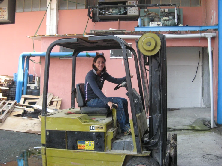 a lady is sitting on top of a fork lift