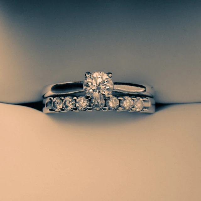 two diamond engagement rings are placed in a shadow