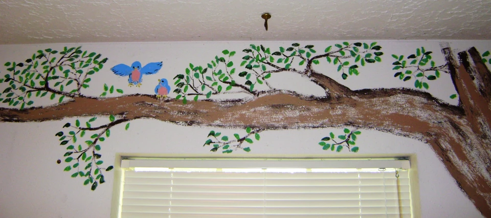 the wall of the bedroom has an tree painted on it