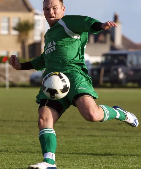 the man is playing soccer outside on the grass